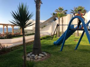 西迪布克纳德尔Luxery stay with seaview, pool, green space & Sunset orientation near Rabat的一个带滑梯和棕榈树的游乐场