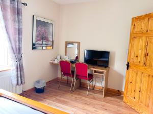 KilcarKilcar Lodge的客房设有一张桌子、两把椅子和一台电视