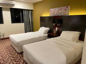 哥打京那巴鲁KK Homestay City Deluxe room - Ming Garden Hotel & Residence的一间酒店客房,房间内设有两张床