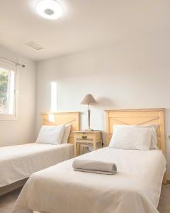 阿尔加德萨Albatross Golf Suite Alcaidesa的一间卧室配有两张带白色床单和灯的床