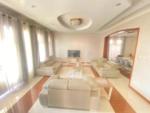 基加利Luxurious very spacious 6 bedrooms villa with pool located in Gacuriro,close to simba center and a 12mins drive to downtown kigali的客厅配有白色家具和电视