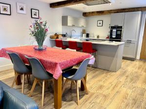 科尔福德Stunning 3-Bed Cottage in The Forest of Dean的一间带红色椅子的桌子的厨房和一间带白色橱柜的厨房