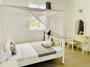 迪亚尼海滩Ammerville Diani的一间卧室配有一张带天蓬的白色床