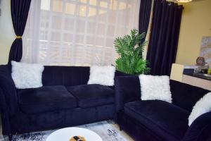 内罗毕Kahawa sukari luxury home的客厅配有带白色枕头的黑色沙发
