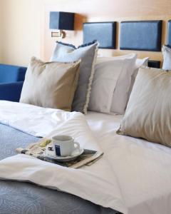 尼亚·卡利克拉提亚爱琴海蓝色海滩酒店 =的白色的床,盘子上放着咖啡