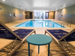 波林布鲁克Home2 Suites By Hilton Bolingbrook Chicago的一个带蓝桌和凳子的游泳池