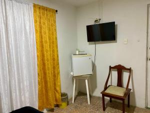 卡塔赫纳Habitación Cerca de aeropuerto的一间黄色窗帘、椅子和电视的房间