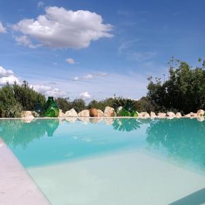 奥斯图尼Trullo Il Melograno的一座蓝色海水和岩石的大型游泳池