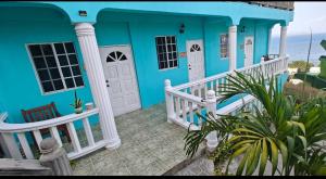 CanouanIsla Vista Apartment Canouan的蓝色的房子,设有白色门廊和大海