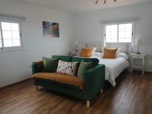 下布雷尼亚Los Frailes的一张绿色的沙发和一张位于客房内的床