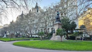 伦敦Apartment London Eye Big Ben walk to China town的建筑物前的女人雕像