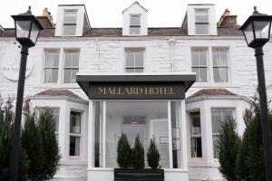 吉伦The Mallard Hotel的一座白色的建筑,上面标有酒店标志