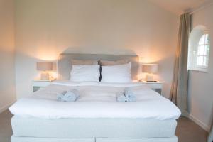 德哈恩Heart at Sea - De Haan的一间卧室配有一张带两盏灯的大型白色床。