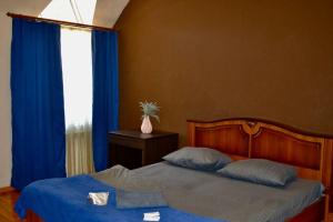 第聂伯罗Отель Ренессанс的一间卧室配有一张带蓝色床单的床和一扇窗户。