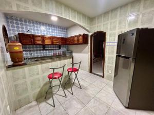 大伊瓜巴La casa magica - A casa mágica的厨房配有2张红色凳子和冰箱