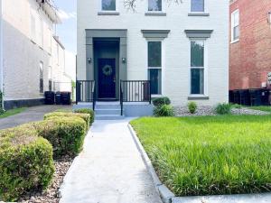 路易斯威尔Mon Fournissuer 4bd Home with backyard的白色的房子,有蓝色的门和绿色的草