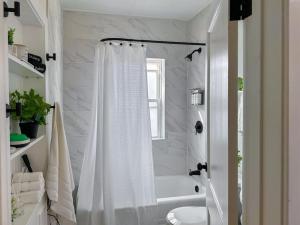 南本德Step into School Spirit at the Golden Dome Getaway的白色的浴室设有淋浴帘和浴缸。