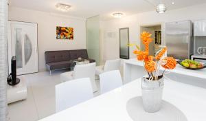 波尔Apartments Šemper - HEATED POOL的白色的客厅配有白色的椅子和橙花花花瓶
