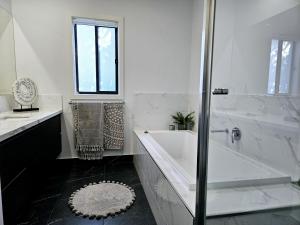 KiallaCharming on Cormorant的白色的浴室设有浴缸、水槽和淋浴。