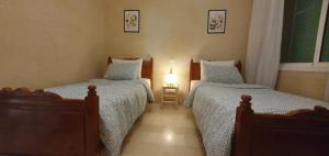 马拉喀什Cozy apartment in the heart of marrakech的一间卧室配有两张单人床和一盏灯。