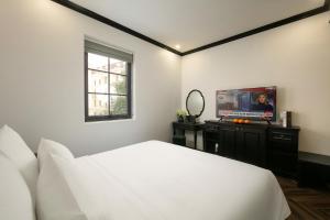 下龙湾Elegant Boutique Hotel Ha Long的一间卧室配有一张床和一台平面电视