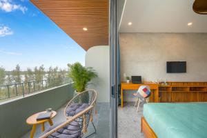 会安Bon Sand Villa & Spa Hoi An的客房设有阳台、一张床和一张书桌
