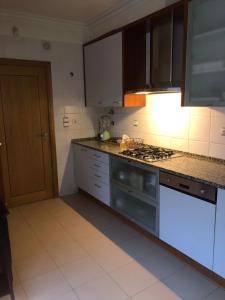 里斯本Apartamento Lisboa的厨房配有白色橱柜和炉灶烤箱。