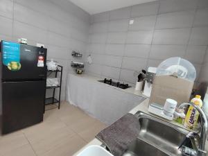 米里JNJ Miri Homestay - Miri Serene Shangrila, Luak with 4-bedroom的厨房配有水槽和黑冰箱。
