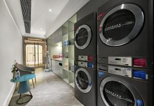 深圳深圳南山深圳湾美居酒店的洗衣房配有3台洗衣机和烘干机