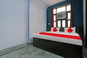 德里OYO Flagship Hotel Elite Inn的一间卧室配有一张带红色枕头的床和一扇窗户