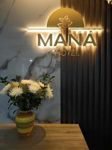 约帕尔HOTEL MANÁ S.A.S.的花瓶,花瓶在麦纳招牌前的桌子上