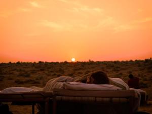 斋沙默尔Explore Hostel Life Jaisalmer的躺在日落前床边的女人