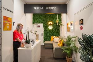 悉尼Tequila Sunrise Hostel Sydney的站在植物房柜台上的女人