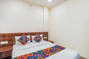 赖布尔FabExpress Convivial Star的一间卧室配有一张带色彩缤纷的床单和枕头的床。