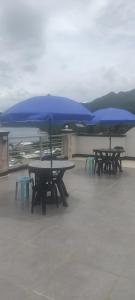 PintuyanD & G Transient House的屋顶上三个带蓝色雨伞的野餐桌