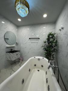 芙蓉Angsamas Villa Seremban Kids Private Pool & Jacuzzi的白色的浴室设有浴缸和吊灯。