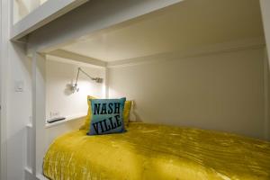纳什维尔121 Hotel by AvantStay Chic Modern Hotel In Nashville的一张黄色的床,上面有蓝色的枕头