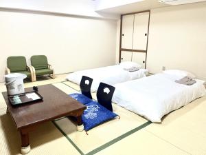 札幌Hotel Tokeidai的一间设有两张床和一张桌子及椅子的房间