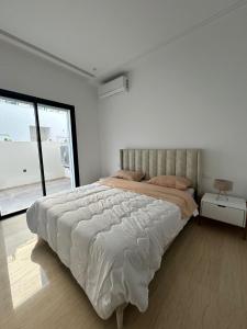 突尼斯joli appartement a jardin de Carthage的白色的卧室设有一张大床和一个窗户