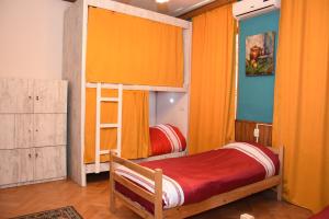 第比利斯Relax Inn Tbilisi的一间卧室配有两张双层床和橙色窗帘
