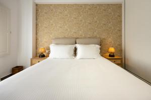 莫诺利索斯FN Suites的一间卧室配有一张带两盏灯的大型白色床。