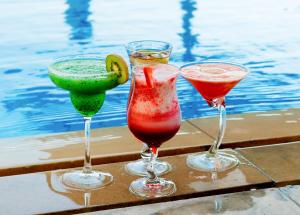 阿布扎比中央阿尔曼哈尔罗塔纳酒店的坐在泳池旁的桌子上,三杯鸡尾酒