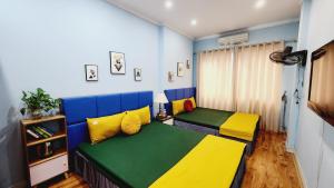 河内Hanoi Cozy Homestay Long Biên的一间卧室设有两张黄色和绿色的床
