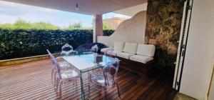 帕劳LOTUS Wellness Apartment - Resort Ginestre - Palau - Sardinia的木甲板上的玻璃桌子和椅子