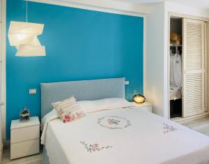 帕劳LOTUS Wellness Apartment - Resort Ginestre - Palau - Sardinia的蓝色的卧室设有白色的床和蓝色的墙壁
