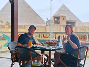 开罗King Pyramids View Hotel的坐在餐桌旁吃饭的男人和女人