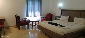 钦奈Mount Heera Hotel-Alandur的一间卧室配有一张床铺、椅子和一张桌子