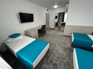 罗曼Hotel Bliss的客房设有两张床、一张桌子和一台电视。