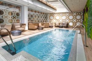 塞维利亚加泰罗尼亚吉拉达酒店的一座带椅子和庭院的酒店游泳池