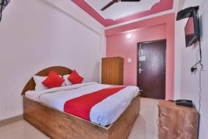 DīghaOYO Hotel Happy Journey的一间卧室配有一张带红色枕头的床和电视。